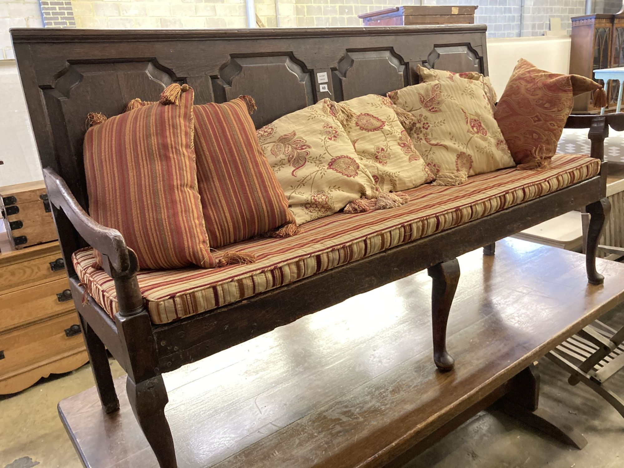 A George III panelled oak settle with rush and squab cushion seat, width 184cm, depth 56cm, height 104cm